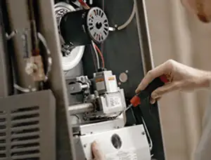 Furnace repair technician inspecting internal components and wiring in Billings, MT
