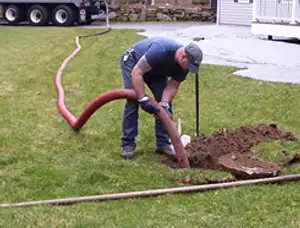 Septic pumping technician servicing a residential septic tank with a vacuum hose in Billings, MT