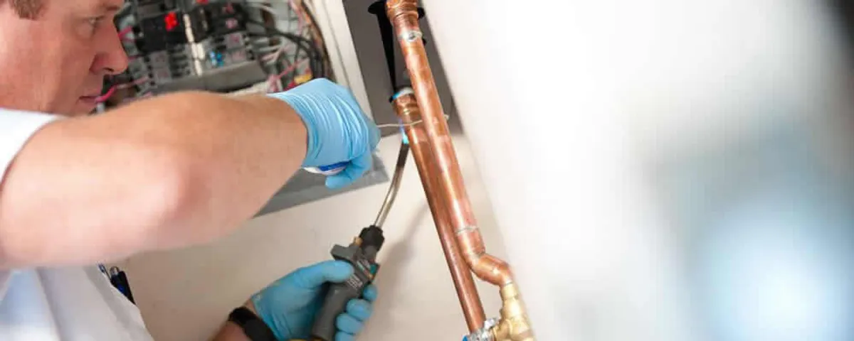 Water heater repair technician testing copper pipe connections and controls in Billings, MT